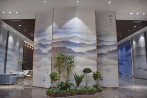 Un área de recepción con un mural de estilo asiático tradicional, una mesa de recepción y un espacio de descanso.