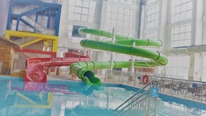 Ein Hallenbad mit mehreren Wasserrutschen und einem Rettungsschwimmerstand.