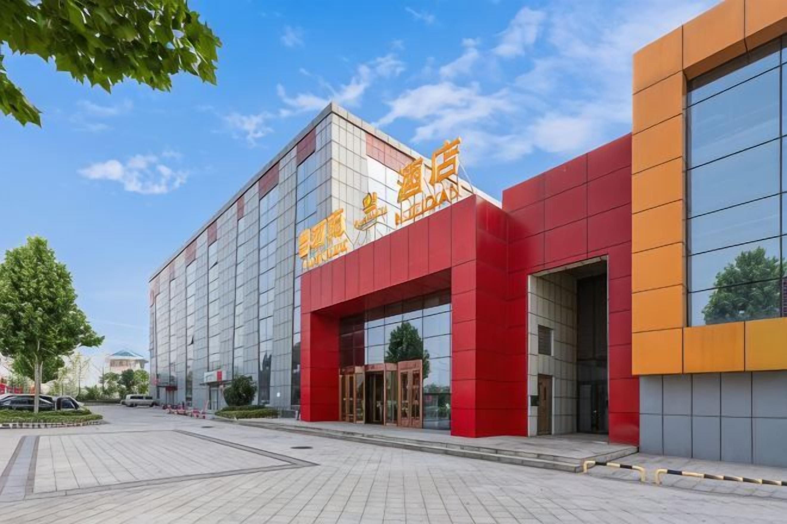 A modern building with a prominent red and yellow facade, large glass windows, and a clear sky.