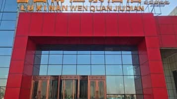 A hotel entrance with a red facade and a clear glass window.