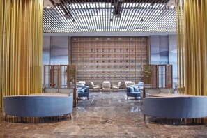 A lobby with a seating area, a wall with a patterned design, and a ceiling with a grid pattern. - Luxinan Hot Spring Hotel (Heze)