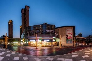 A modern building with a curved facade, large windows, and a prominent advertisement on the side.