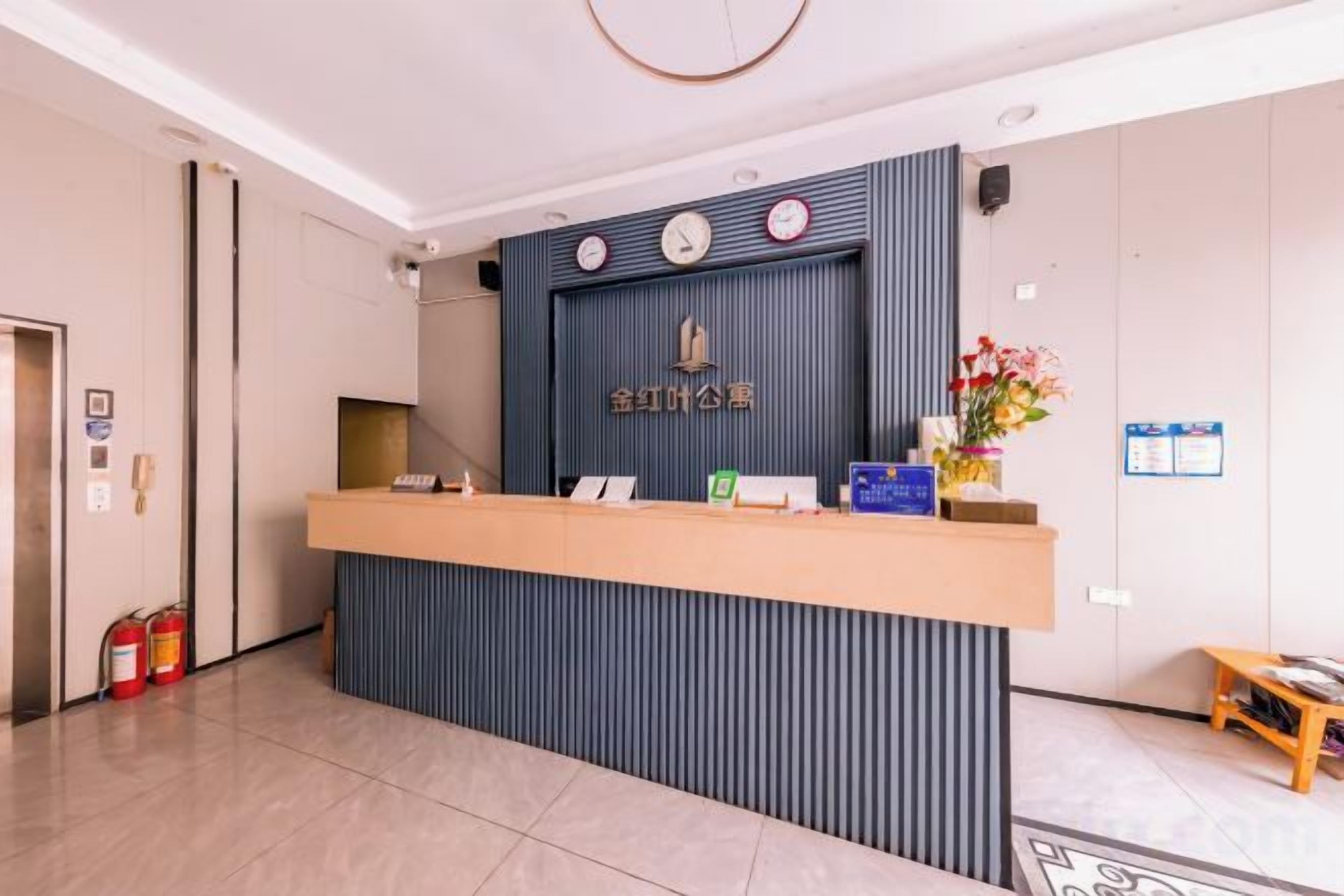 A reception desk with a clock, a fire extinguisher, and a small table with flowers.