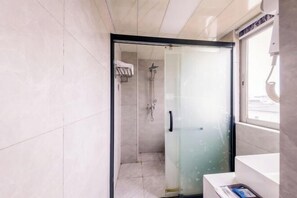 Un baño moderno con cabina de ducha de vidrio, un lavabo blanco y un perchero para toallas.