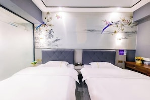 Een hotelkamer met twee bedden, een grote spiegel en een wanddecoratie met vogels en bloemen.