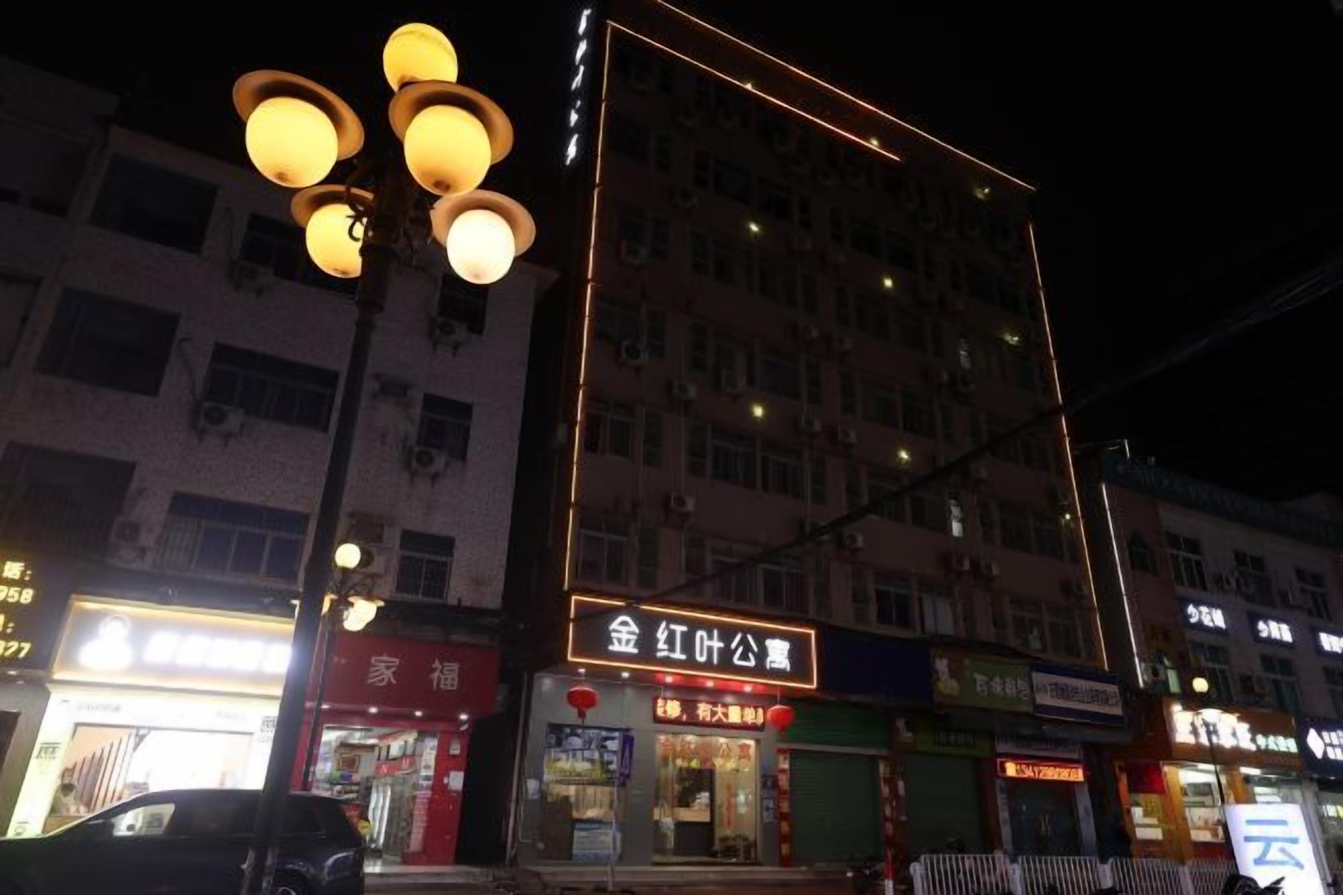 A multi-story building with illuminated signage, a street lamp, and a parked car.