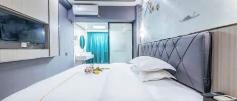 Habitación de hotel con cama, mesita de noche y televisor montado en la pared.