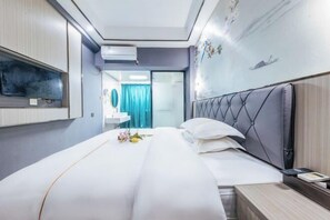 Habitación de hotel con cama, mesita de noche y televisor montado en la pared.