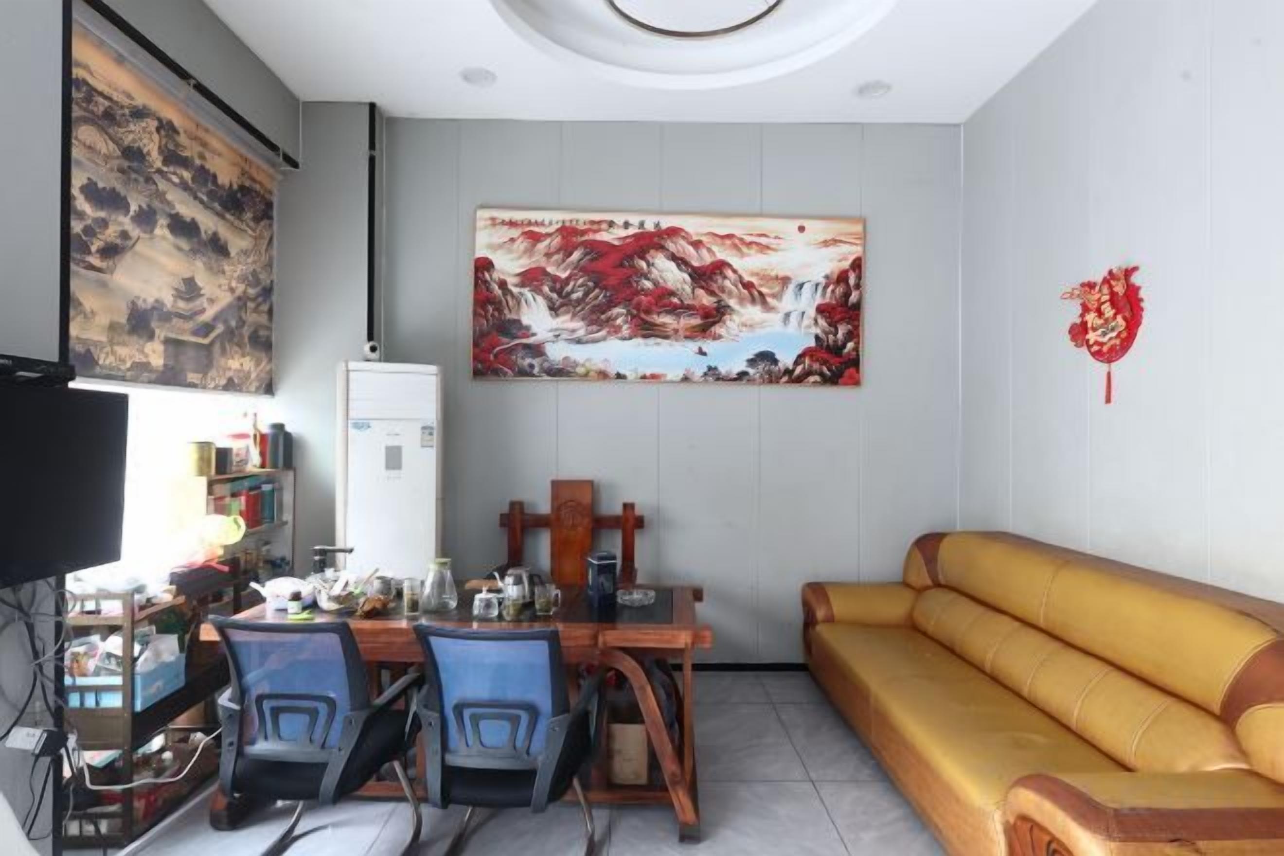 Ein Wohnzimmer mit Sofa, einem Esstisch mit Stühlen, Fernseher und Kunstwerken an den Wänden.