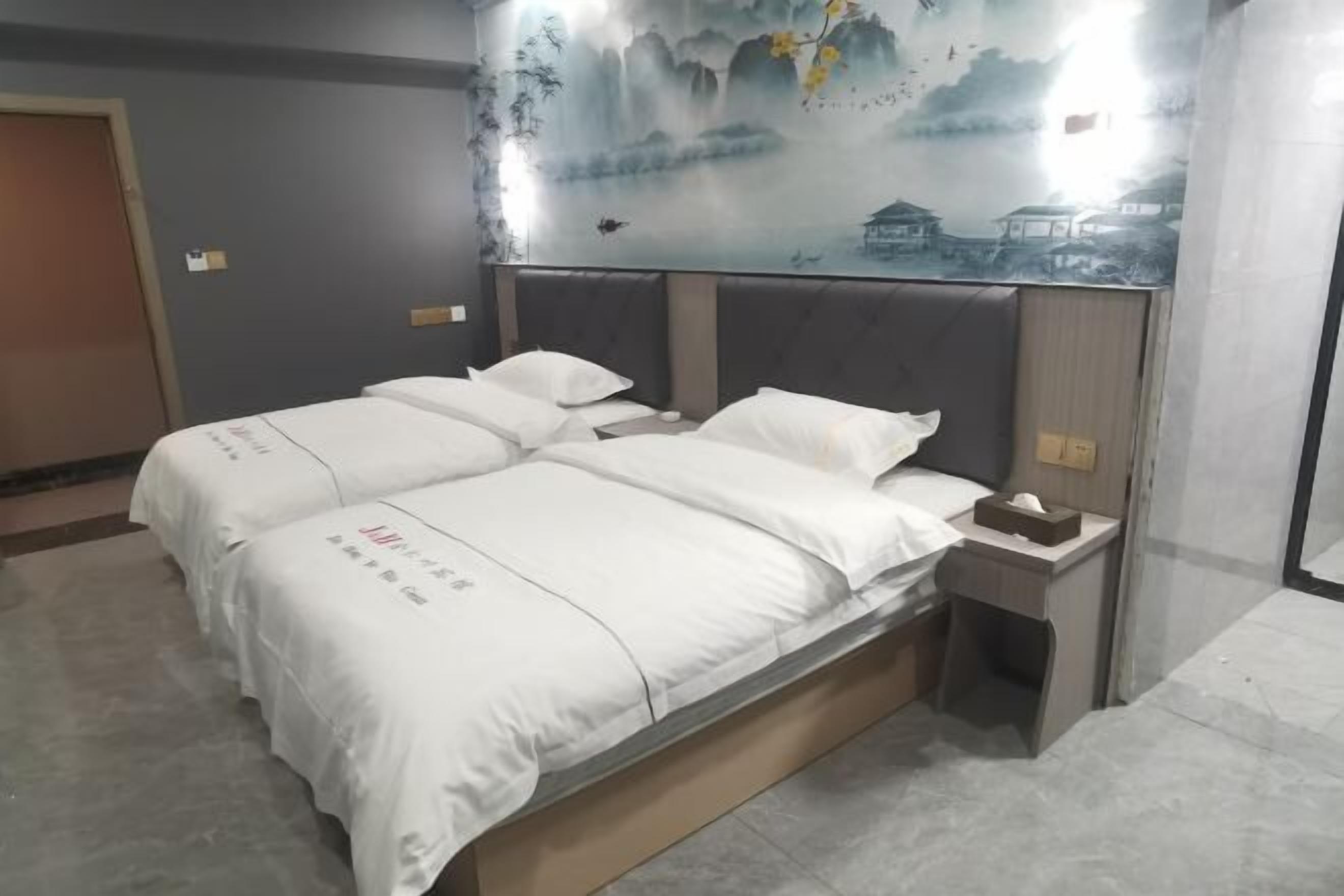 A hotel room with a bed, a nightstand, and a wall mural.