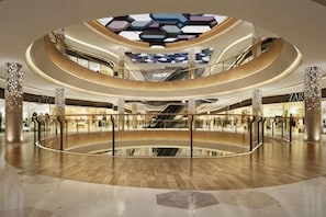 A multi-level atrium with a central open space, escalators, and a glass ceiling.