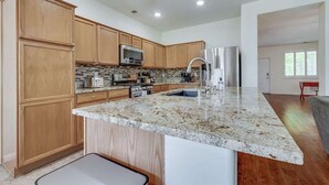 A modern kitchen with wooden cabinets, granite countertops, stainless steel appliances, and a large island. - ☀Cheerful Family Getaway ~ Large & Sunny Backyard☀ (Sparks)
