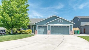 A residential house with a garage, driveway, and a tree. - ☀Cheerful Family Getaway ~ Large & Sunny Backyard☀ (Sparks)