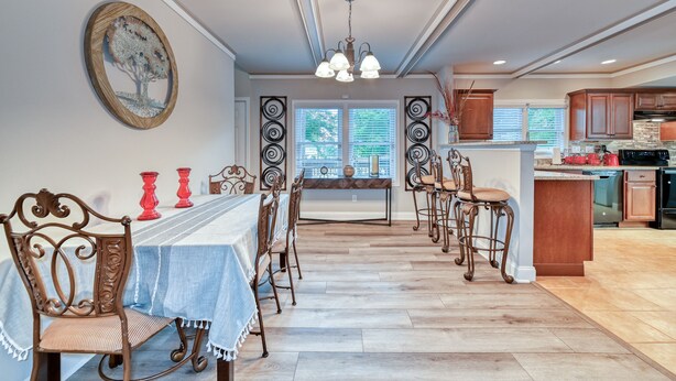 A dining area with a long table, chairs, and a chandelier.