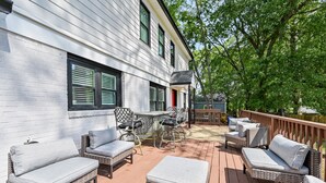 A covered deck with wicker furniture and a brick wall.