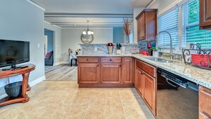 A modern kitchen with wooden cabinets, a granite countertop, and a built-in dishwasher.