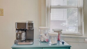 A coffee maker on a teal cabinet with coffee pods and a water container.