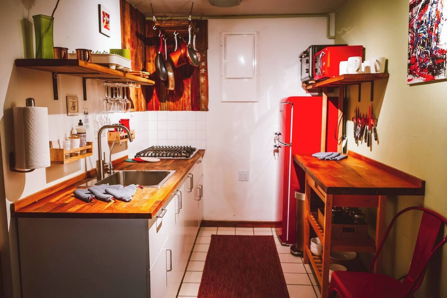 A compact kitchen with a wooden countertop, a sink, a stove, and a refrigerator.