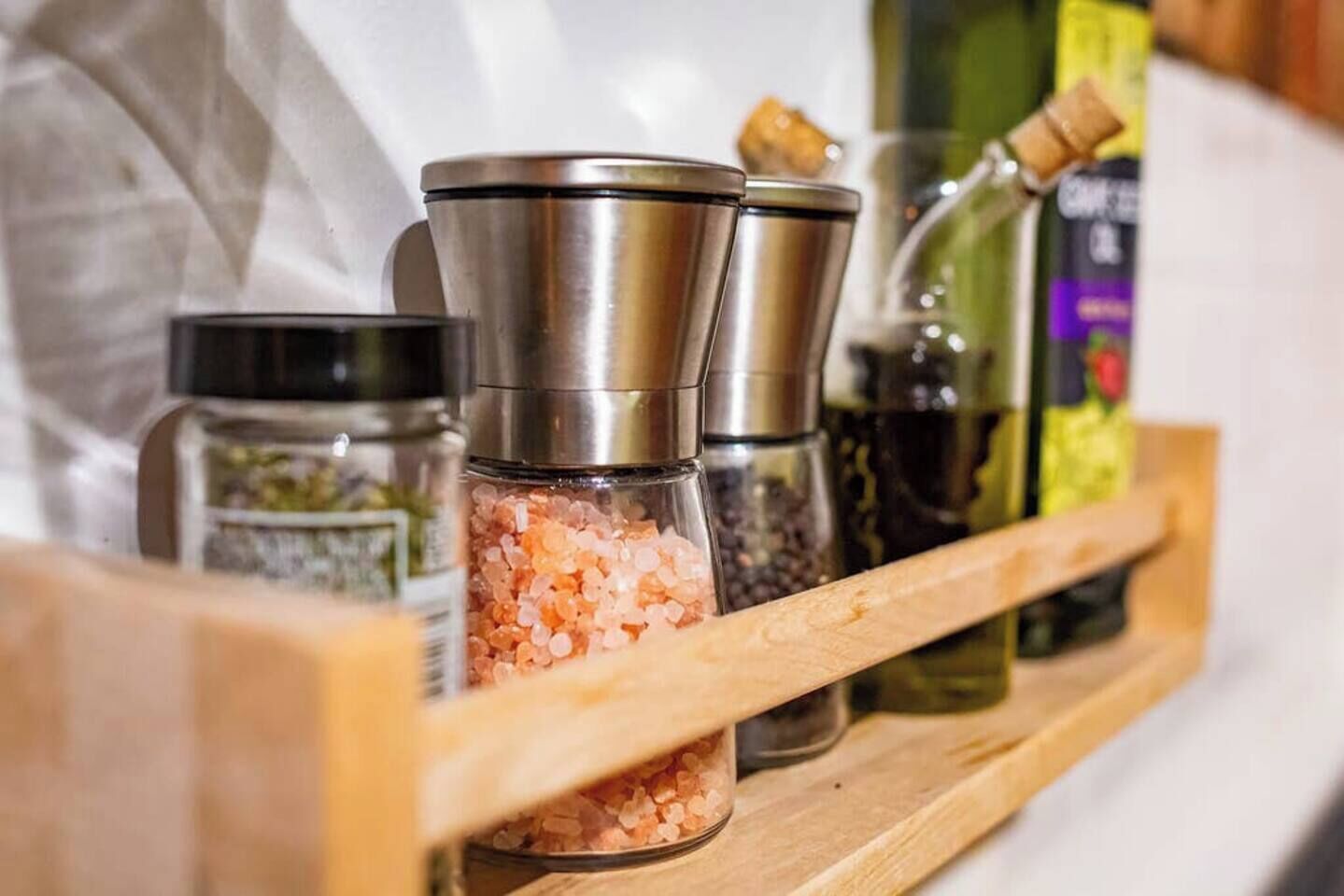 A wooden shelf with various kitchen items including salt shakers and spice containers.