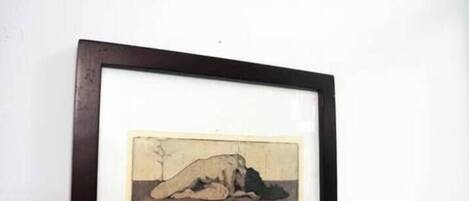 Una obra de arte enmarco, una concha marina y una estrella de mar sobre una pared blanca.