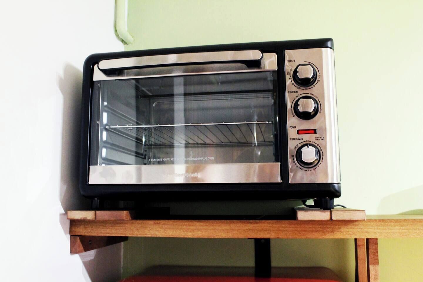 Horno tostador de acero inoxidable con puerta de vidrio, perillas de control y dial para temporizador/minutos.