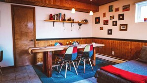 A cozy room with a wooden table, chairs, and a bed. There are shelves with books and decorative items on the wall, and a window with a view. - Dream getaway apartment in the foot of Gunks Ridge (Wallkill)