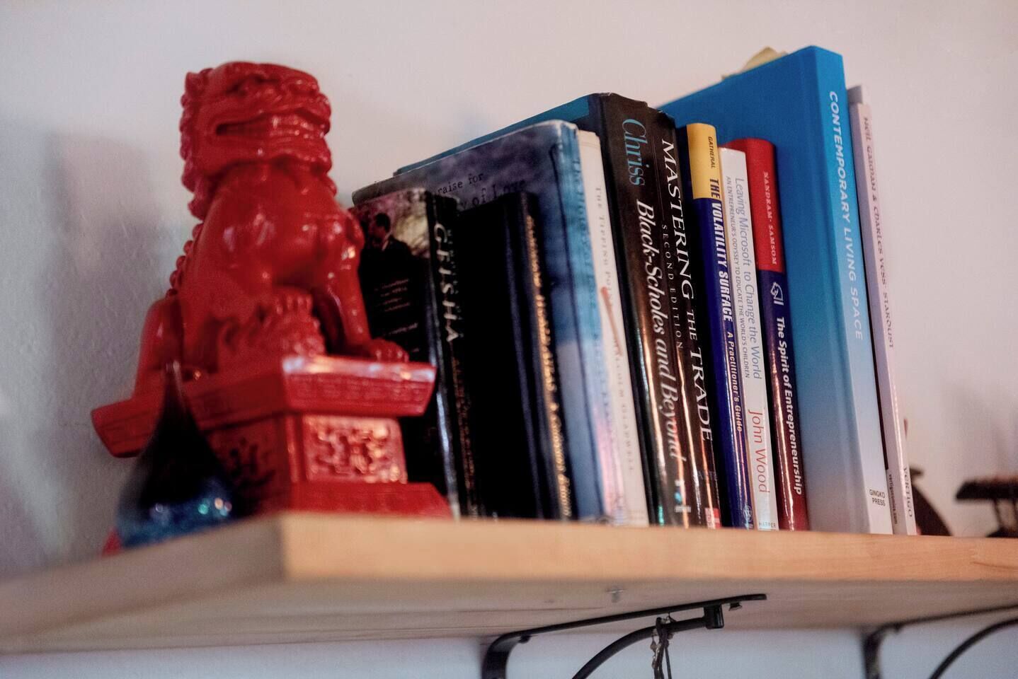 A shelf with books and a red figurine.