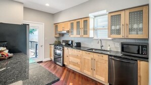 Una cocina moderna con armarios de madera, lavavajillas de acero inoxidable y microondas negro.