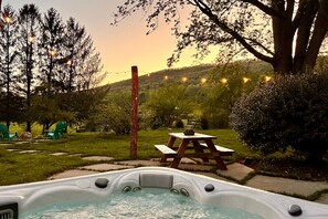 Ein Whirlpool in einem Garten mit Picknicktisch und Lichterketten.
