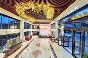 A spacious lobby with a high ceiling, a reception desk, and a view of the parking area. - Yishan Banshui Hotel (Xing'an County)