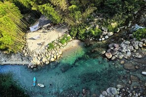 A beach with clear water, rocks, and a small hut.