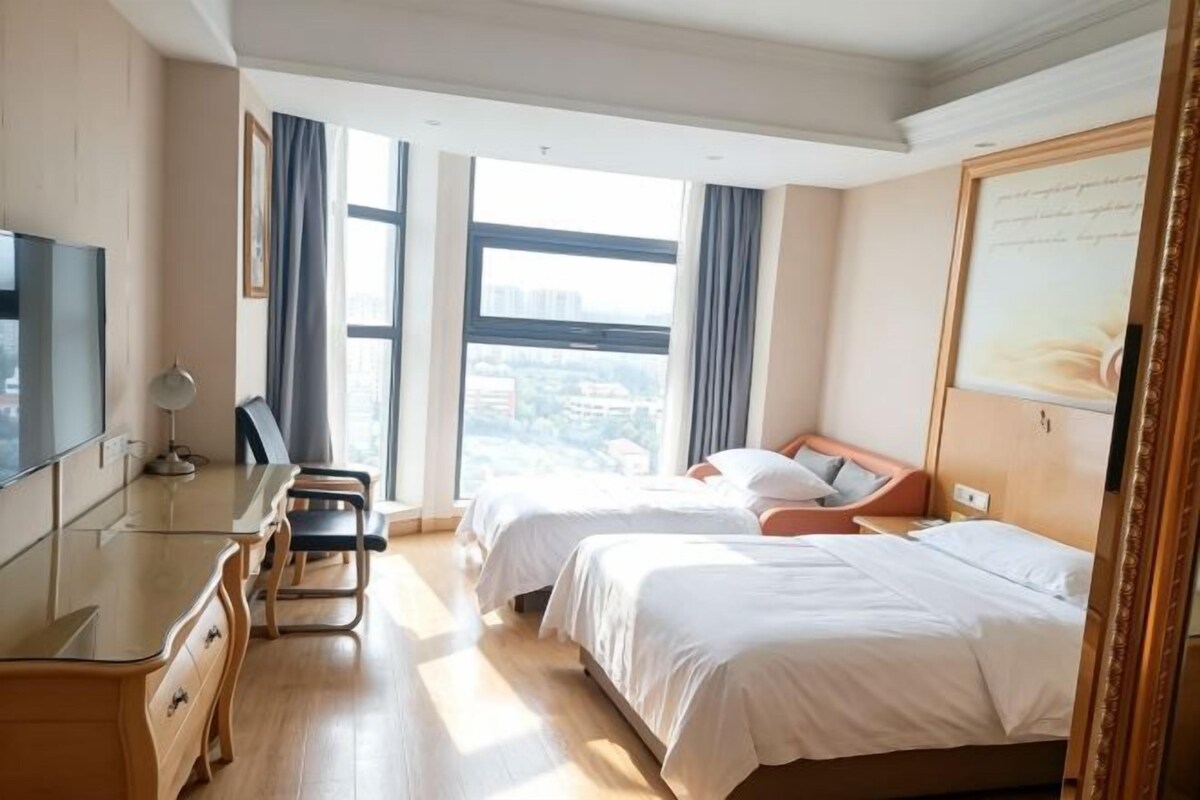 Una habitación de hotel con cama, escritorio y televisor.