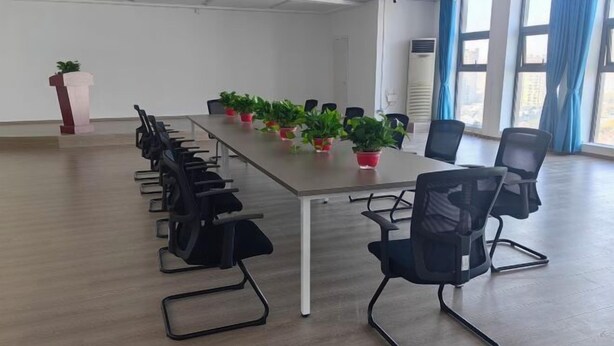 A conference room with a long table, black chairs, and potted plants. - Vienna Hotel (Yixing High-speed Railway Station) (Yixing)