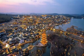 A traditional village with a prominent pagoda and a river. - Vienna Hotel (Yixing High-speed Railway Station) (Yixing)