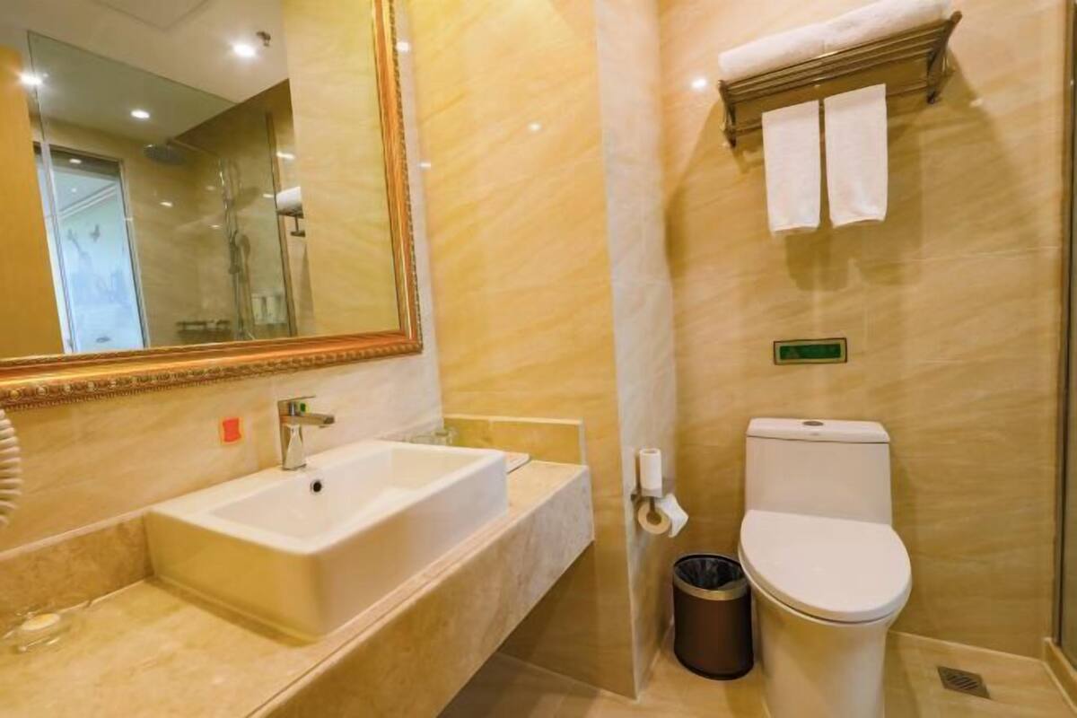 A bathroom with a sink, toilet, and mirror.