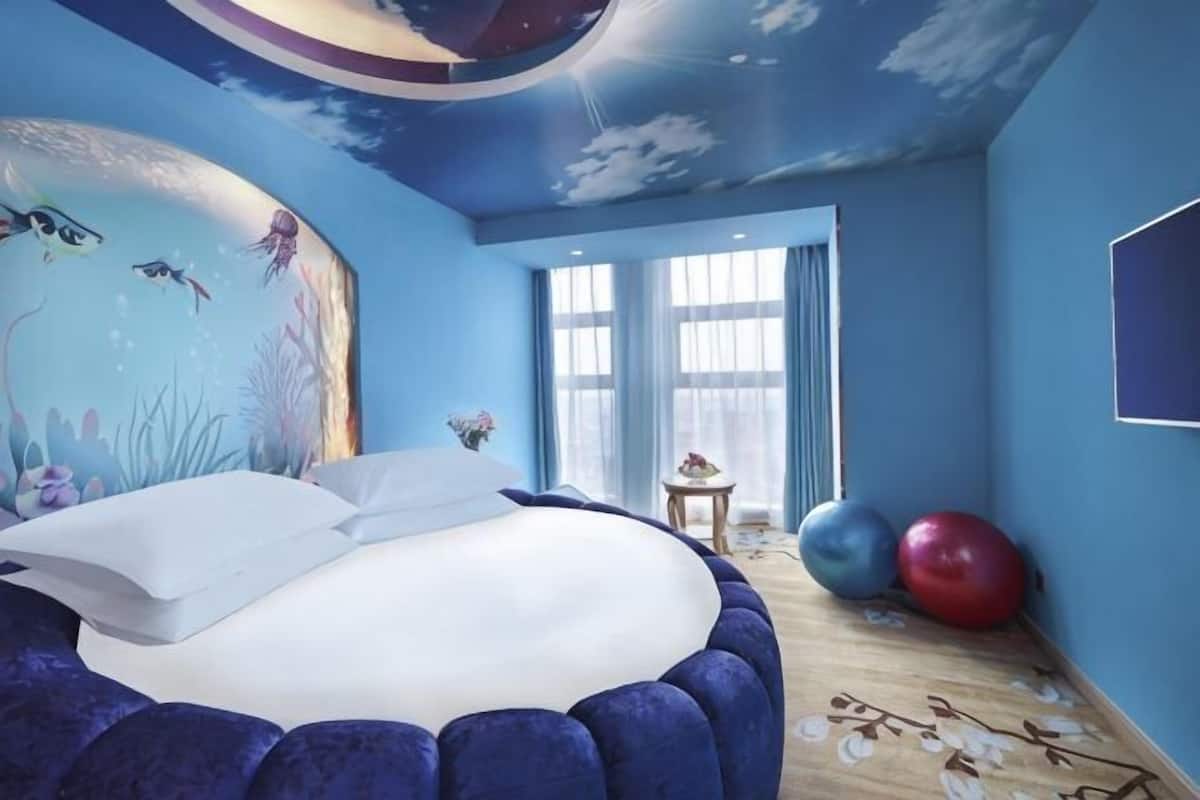A bedroom with a bed, a mural, a window, and exercise balls.