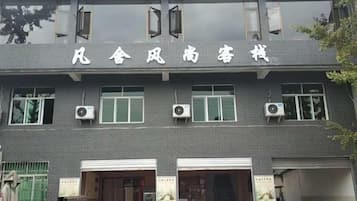 A building with a sign that reads 'Feng Chao Wind and Rain Pavilion.' There are air conditioning units on the exterior, and two open doors at the ground level.