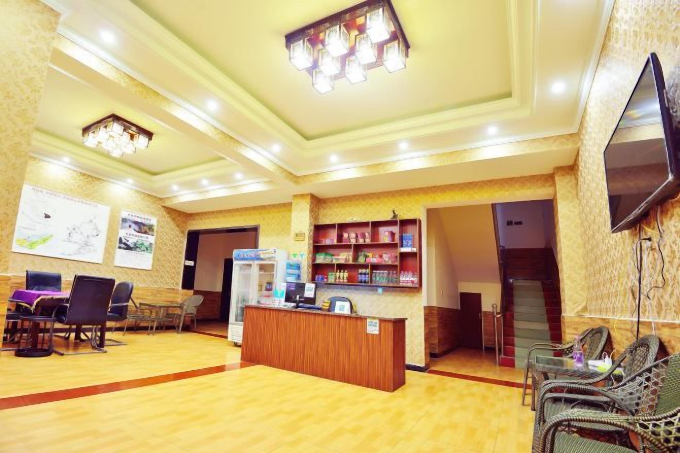 A hotel lobby with a reception desk, seating area, and a staircase leading to other floors.