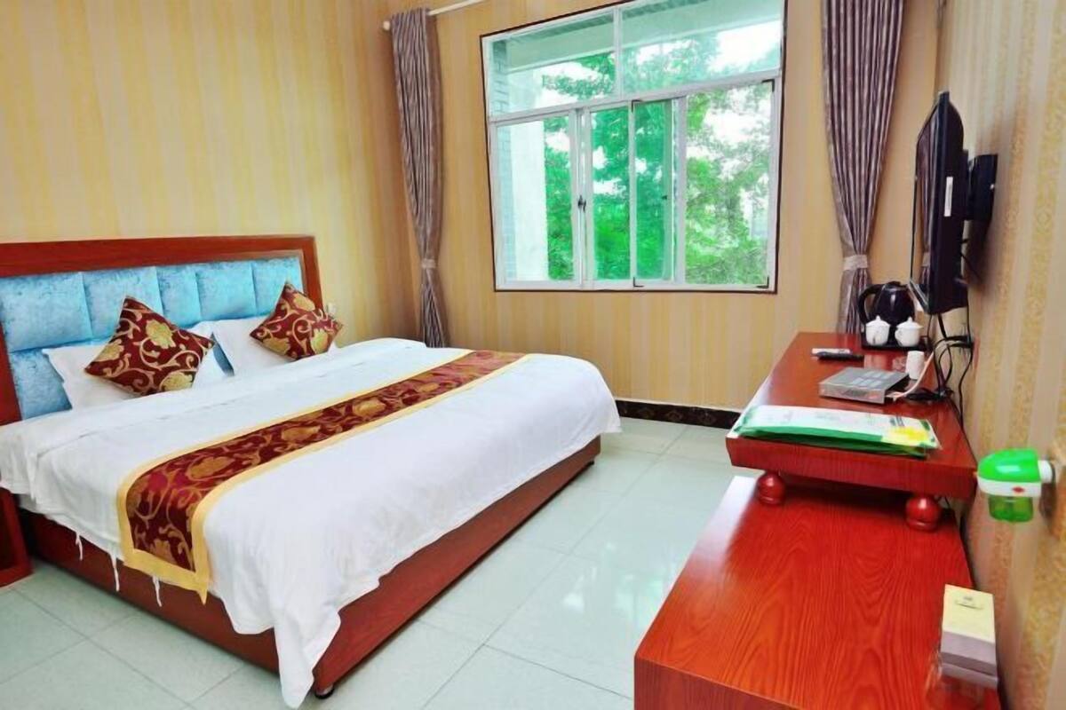 A hotel room with a bed, a desk, a TV, and a window with curtains.