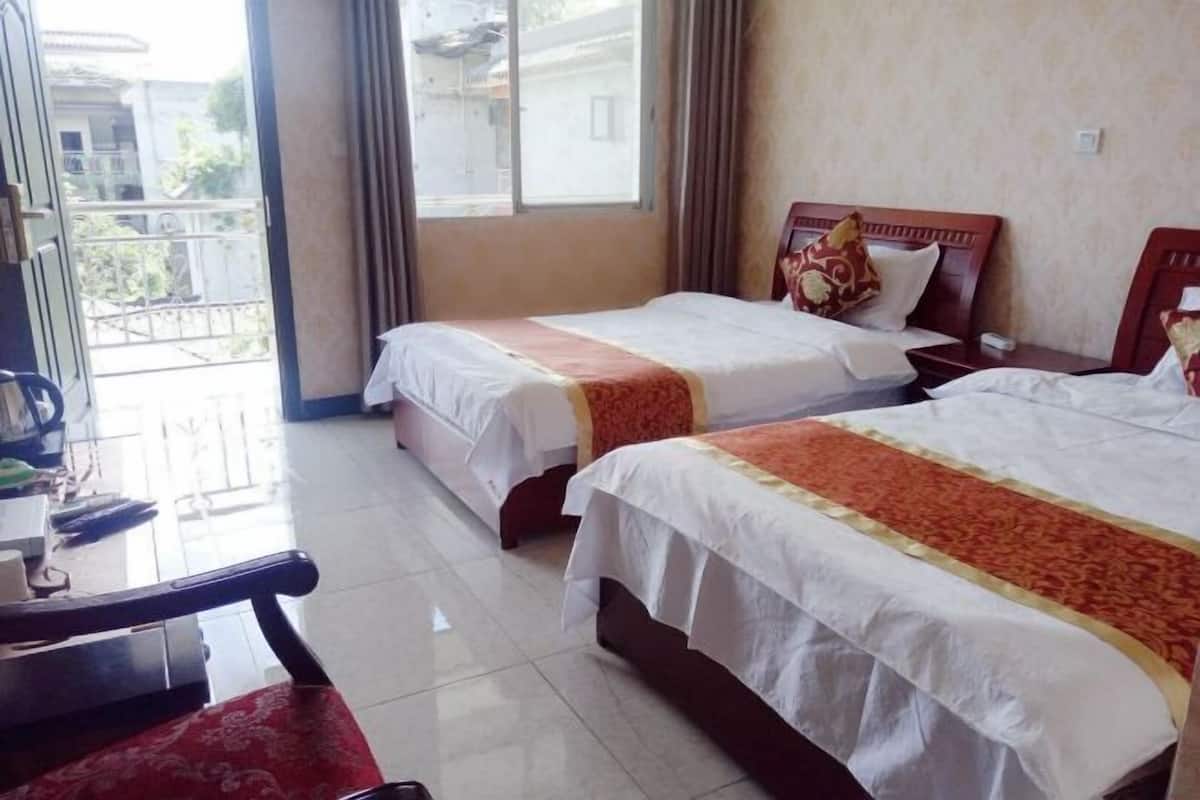 A hotel room with two beds, a desk, and a chair.