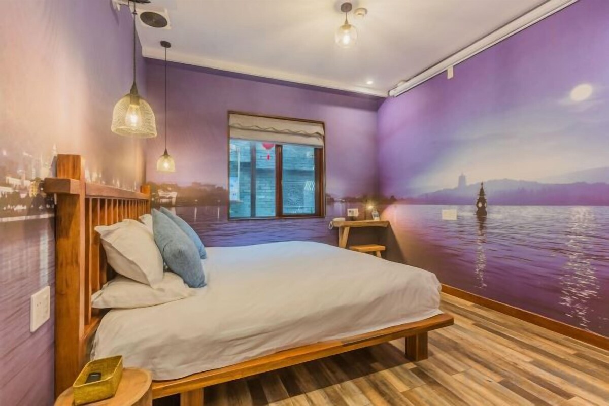 A bedroom with a bed, a nightstand, a window, and a wall mural.