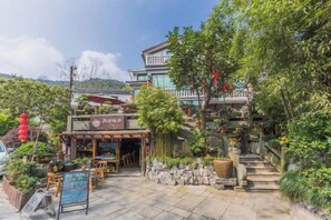 A restaurant with outdoor seating, surrounded by greenery and a staircase leading to a building. - Hangzhou Zhangshe Courtyard Homestay (Hangzhou)