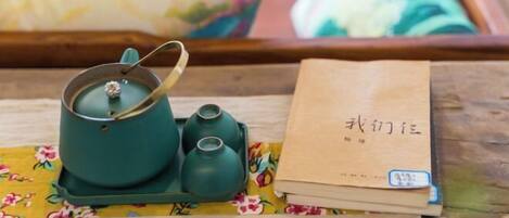 A wooden tray with a teal teapot, two small teacups, and a brown book with Chinese characters.