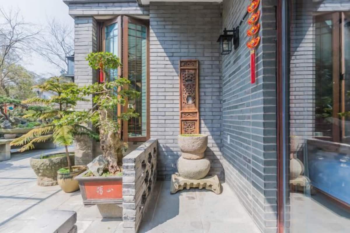 Een gebouw met een stenen gevel, traditionele Chinese versieringen en potplanten.