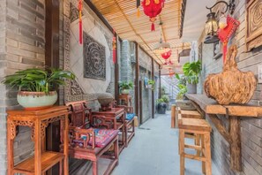 A narrow corridor with traditional wooden furniture, potted plants, and decorative wall elements. - Hangzhou Zhangshe Courtyard Homestay (Hangzhou)