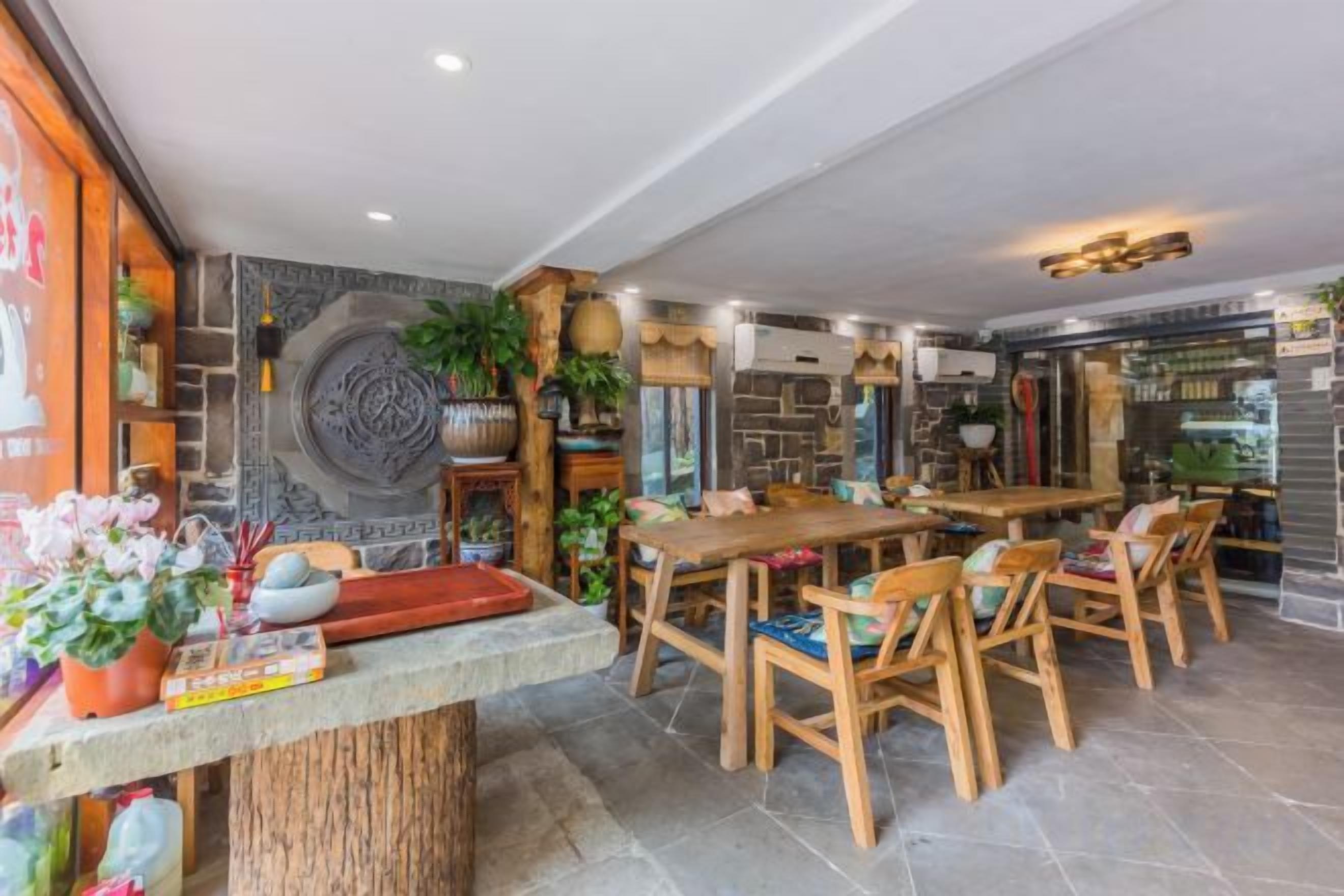 Un restaurante con pared de piedra, mobiliario de madera y una variedad de plantas.