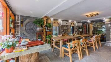 Un restaurante con pared de piedra, mobiliario de madera y una variedad de plantas.