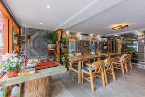 A restaurant with a stone wall, wooden furniture, and a variety of plants. - Hangzhou Zhangshe Courtyard Homestay (Hangzhou)