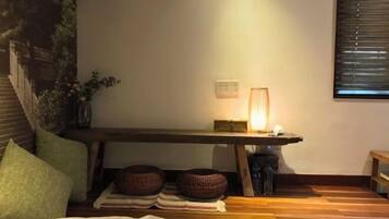 Un dormitorio acogedor con cama, almohadas, una mesita de noche con lámpara y una ventana con persianas.