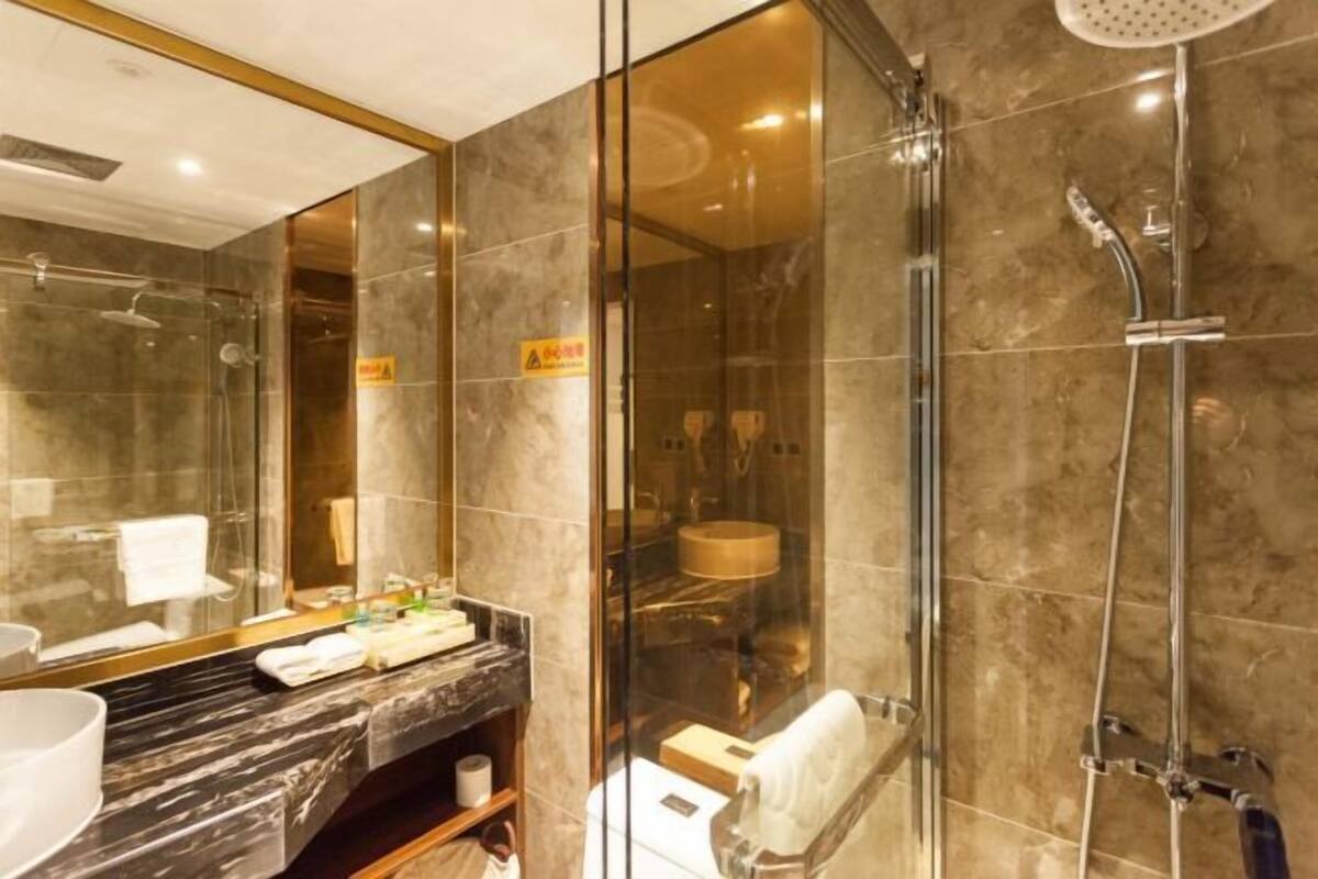 A modern bathroom with a glass shower enclosure, a marble countertop, and a large mirror.